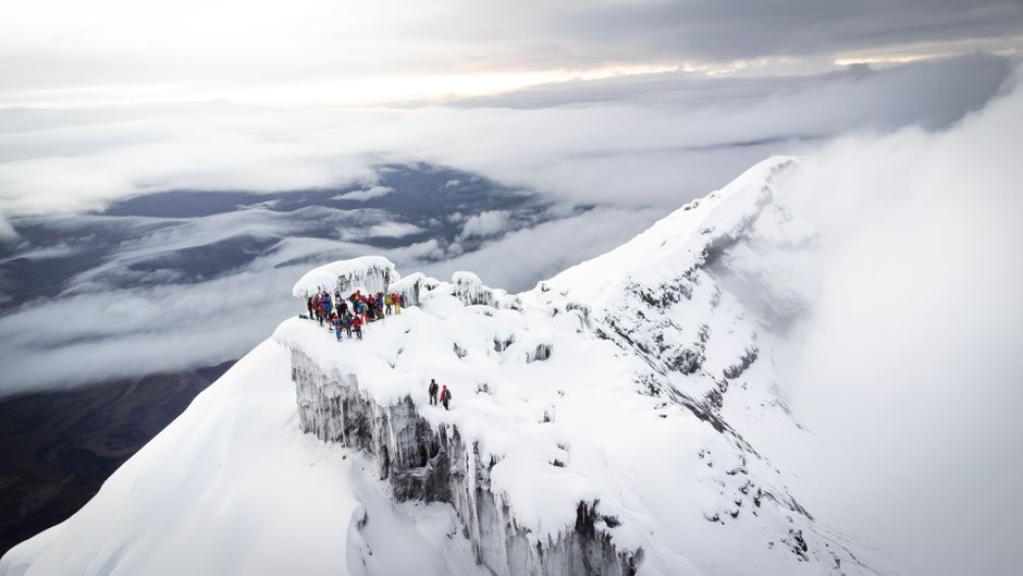 Unbeatable Middle of the World Tour and Hummingbird Reserve Review: Standing Where the Planet Divides Review 2026 - Climbers reach the snow-covered summit of Cotopaxi Volcano in Ecuador, surrounded by dramatic clouds.