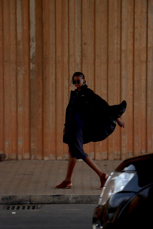 Free Elegant woman in dark outfit walking under city bridge conveying urban chic. Stock Photo
