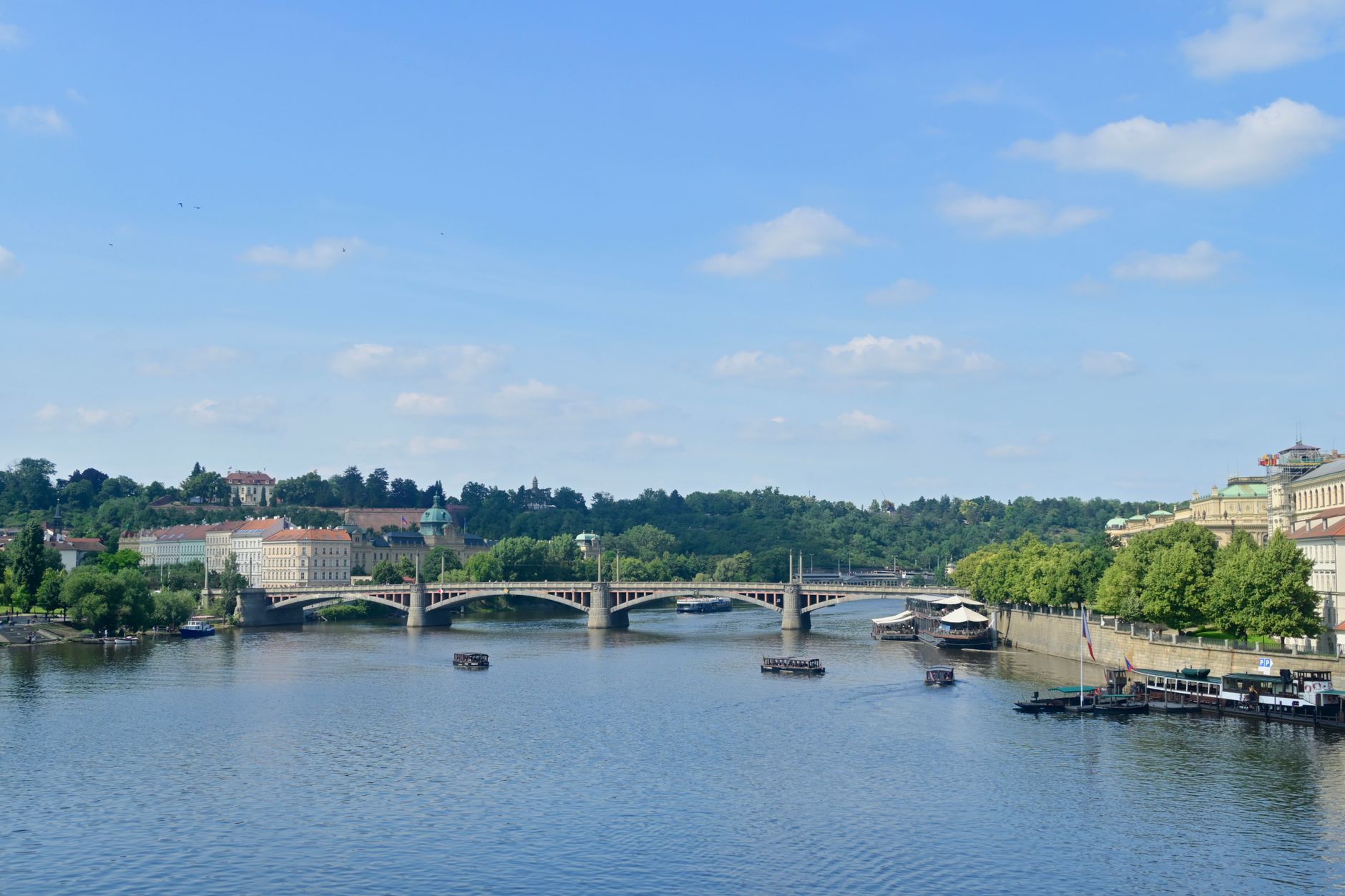 Scenic view of Vltava River and historic architecture in Prague on a sunny day.