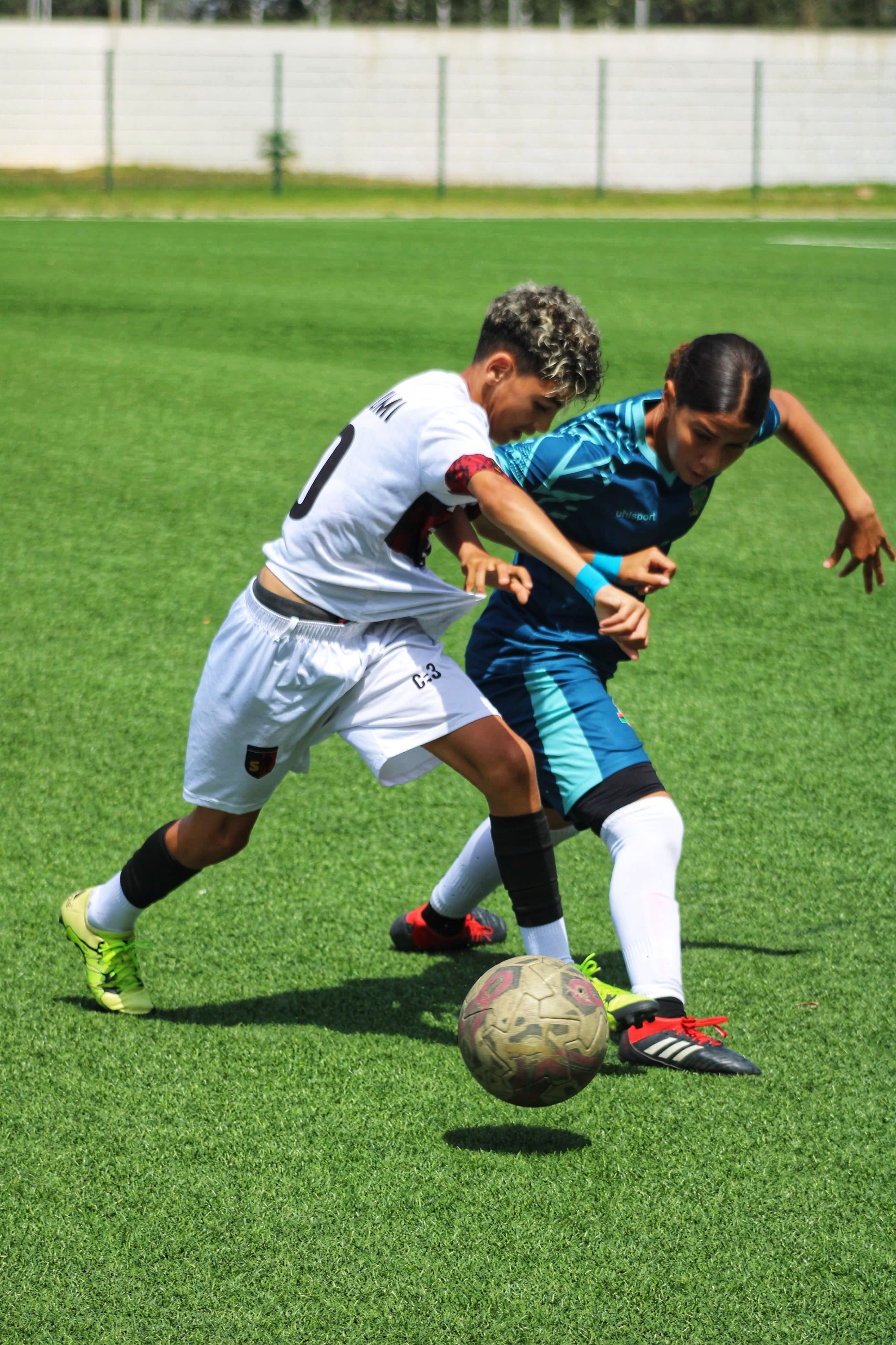 Two youth soccer players competing during a match on a sunny day.