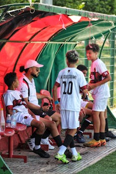 Teen soccer players resting on a bench, preparing for their next game move.