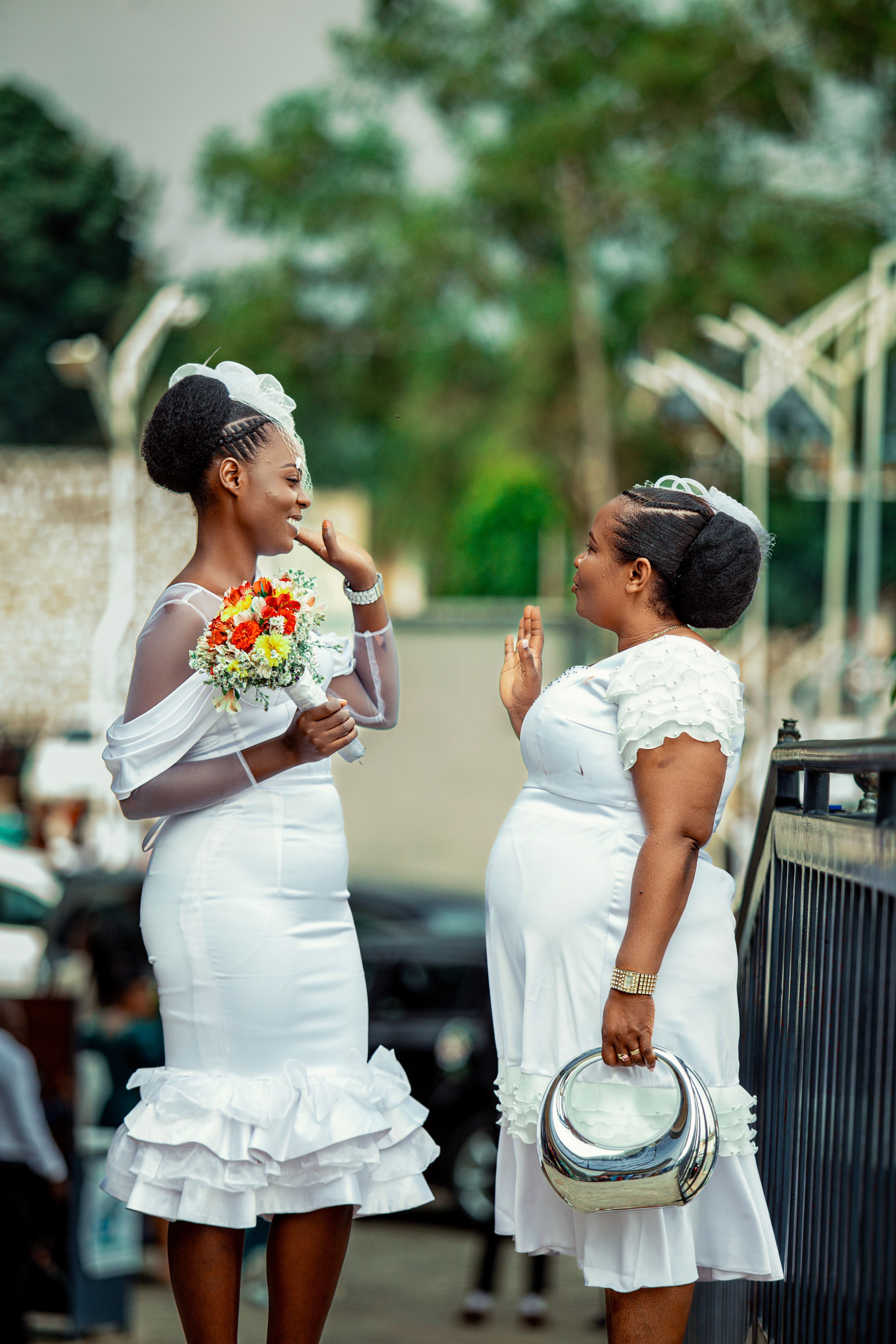 Two Women in White Dresses Engaging Outdoors · Free Stock Photo