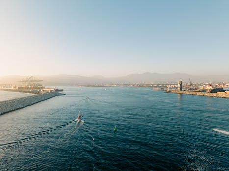A serene aerial view of a coastal port under a clear sky at sunrise.