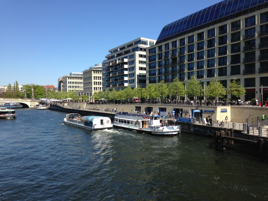 View of the vibrant Spree River with modern buildings and boats in Berlin.
