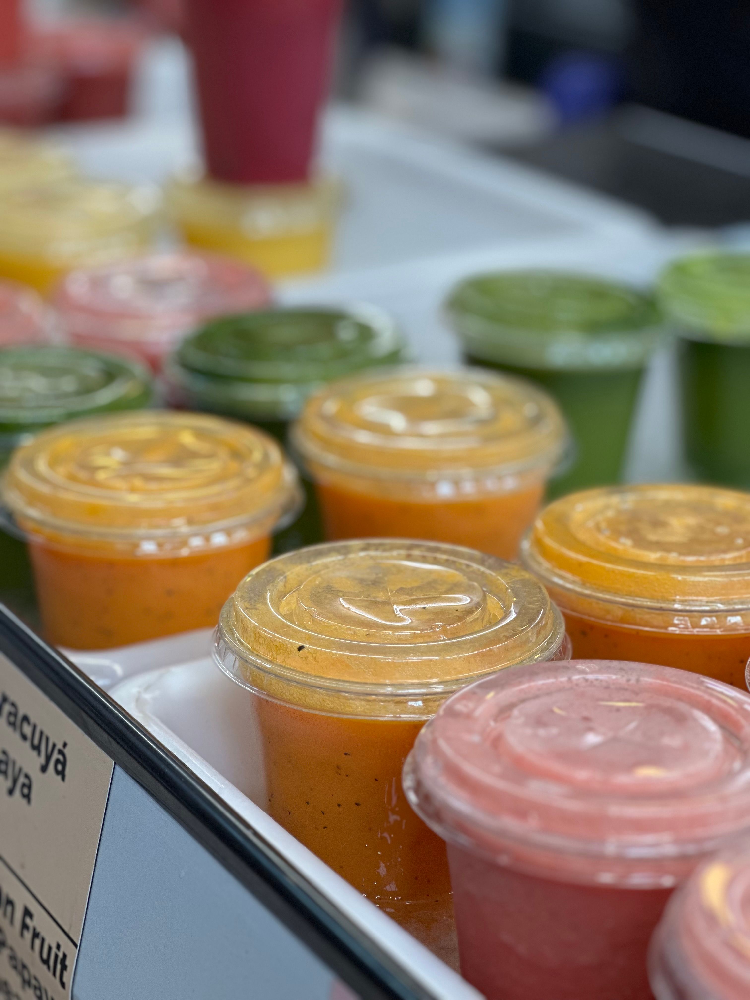 Vibrant fresh fruit smoothies displayed at an outdoor juice bar, ideal for a refreshing summer drink.