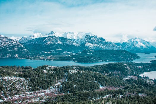 晴朗的天空下，白雪皑皑的山脉与宁静的湖泊尽收眼底