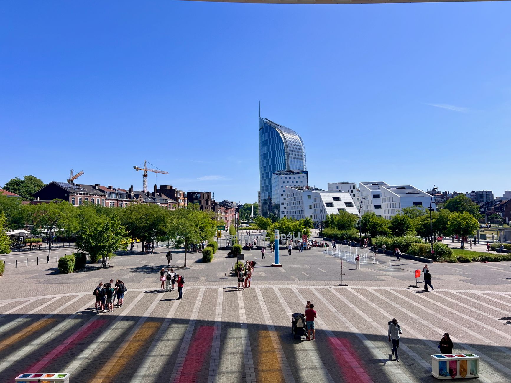 View of a vibrant urban street in Liège with modern architecture and clear blue skies.