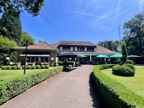 Beautiful outdoor view of a charming restaurant surrounded by lush greenery and a well-maintained garden pathway.