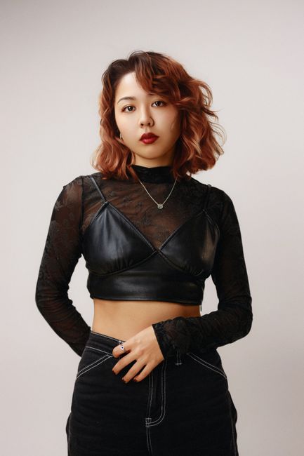 Portrait of a young woman wearing a leather top and black jeans, exuding confidence.