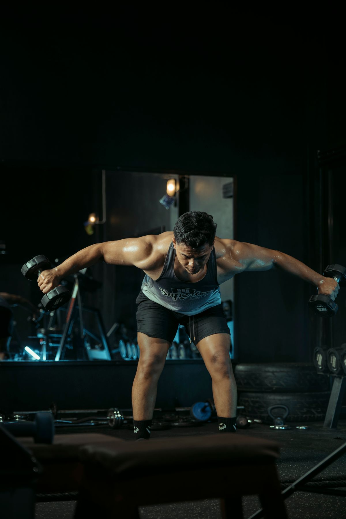 Athlete lifting dumbbells in a dark premium gym