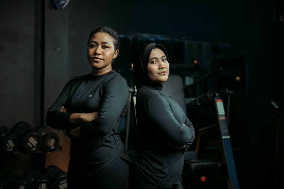 Two confident women stand strong in a gym, ready to tackle their workout challenges.