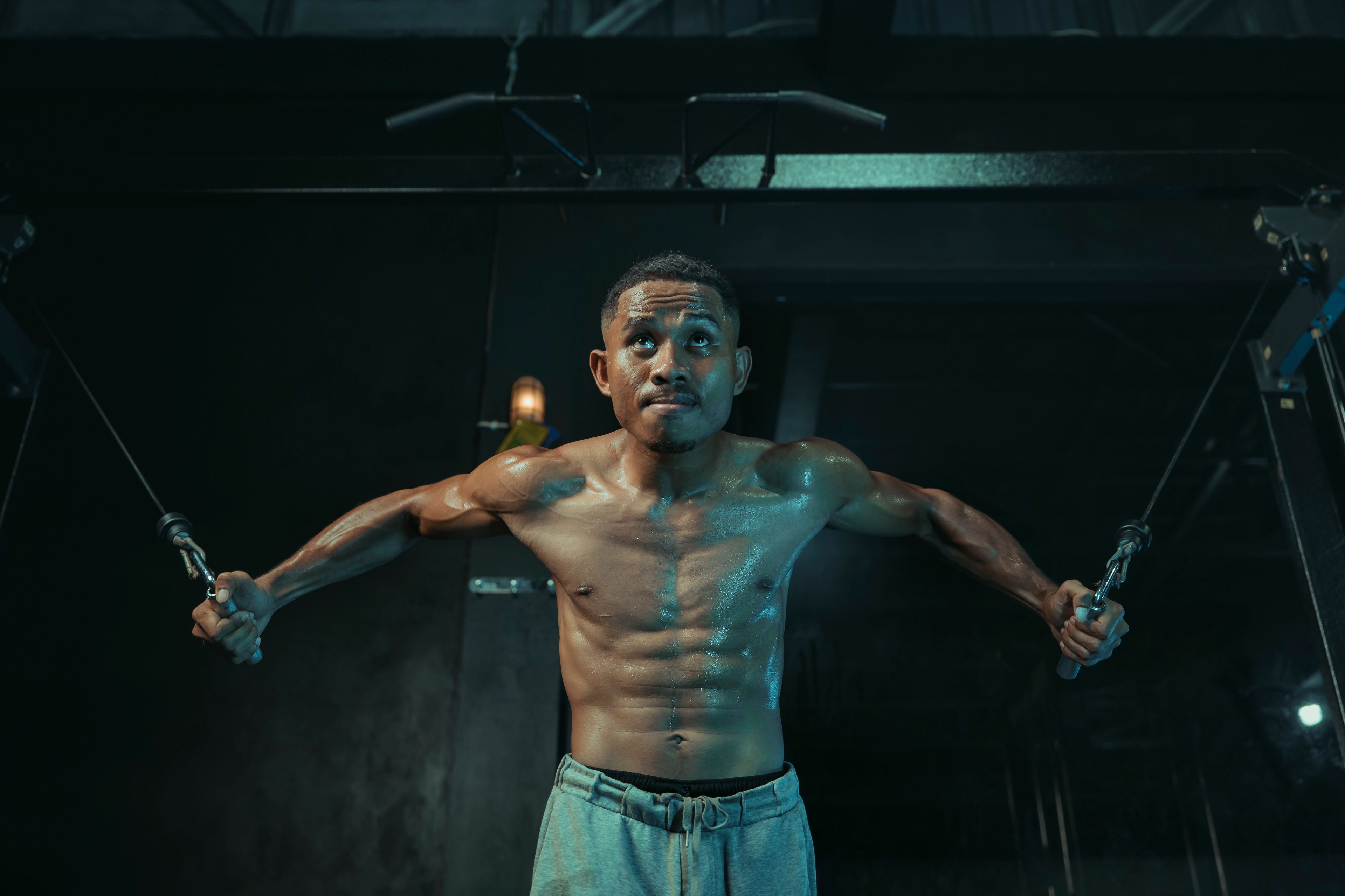 Fit male athlete focusing during intense cable fly workout in a gym setting.