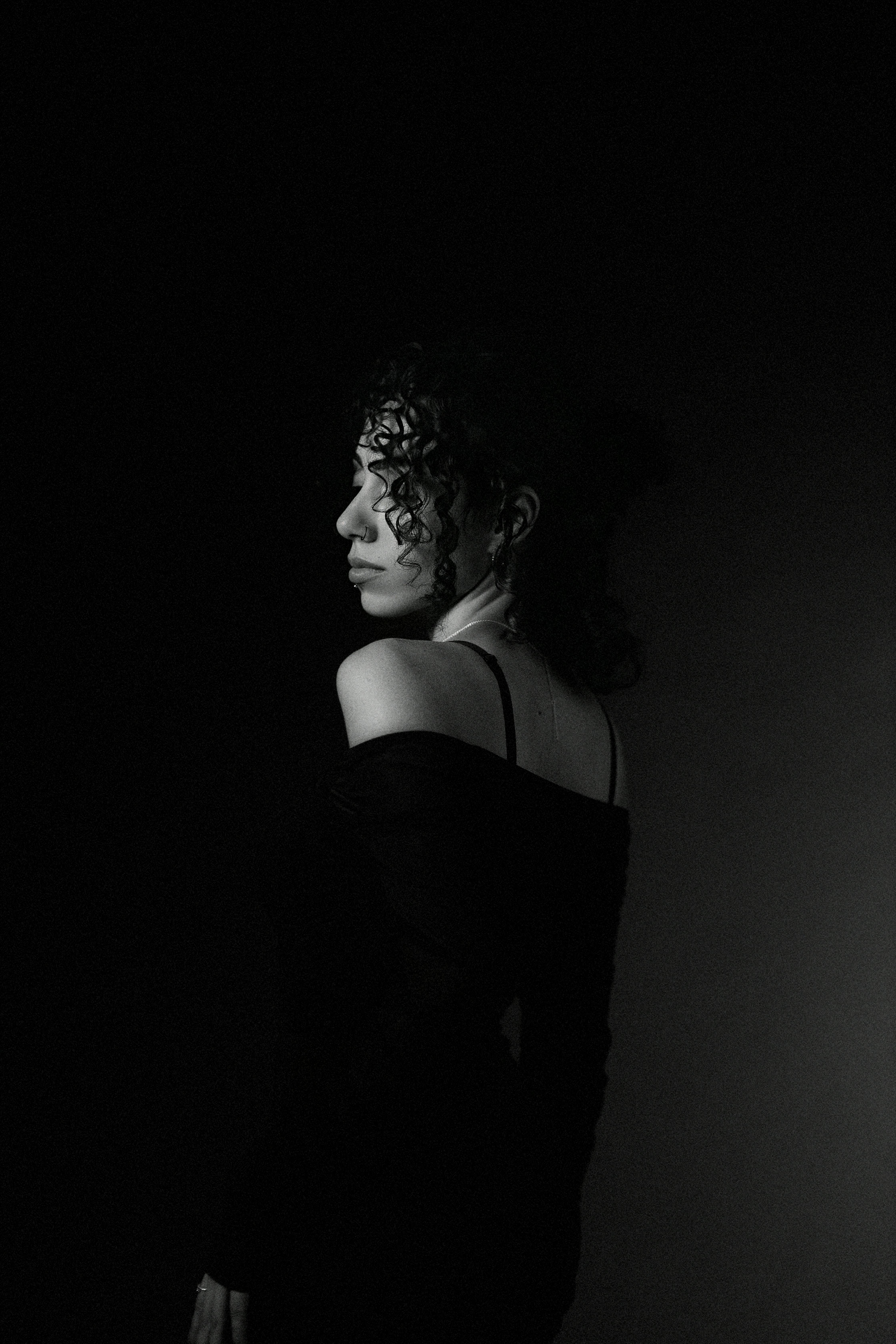 Elegant and moody black and white portrait of a woman in profile with soft lighting.