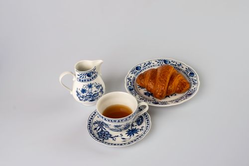 Free Aesthetic still life featuring a cup of tea, croissant, and porcelain dishes on a white backdrop. Stock Photo