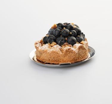 Mouthwatering blueberry tart with powdered sugar on a minimalist white backdrop.