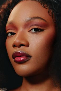 Close-up portrait highlighting bold makeup on a beautiful woman with striking features and confident expression.