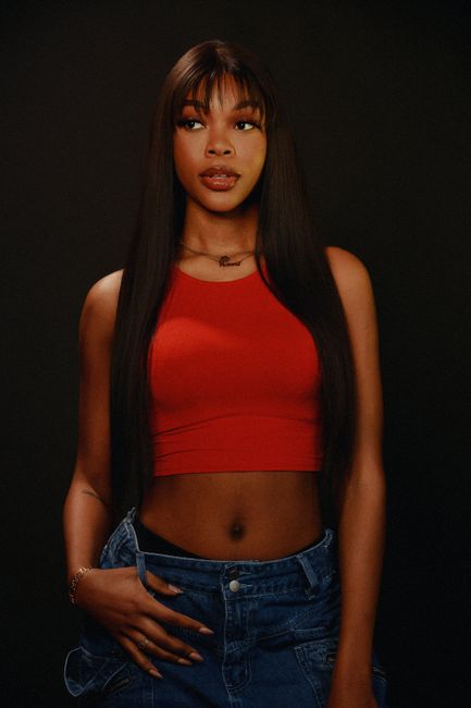 A captivating portrait of a stylish woman in a red top against a dark background, exuding confidence and elegance.