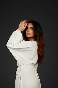 Chic portrait of a woman in a white dress on a dark background.