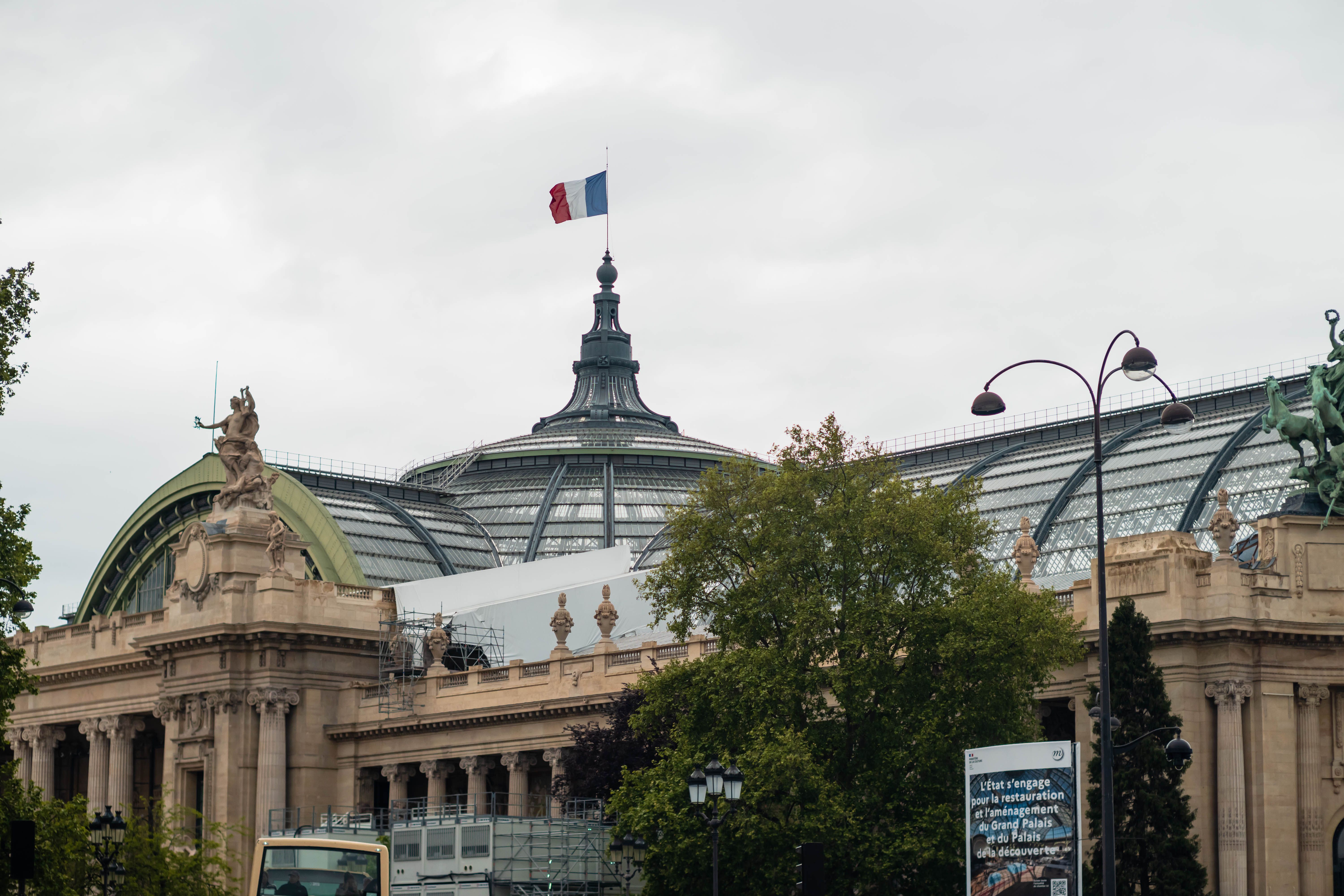 Vue du Grand Palais à Paris avec le dôme de verre emblématique et le drapeau français.