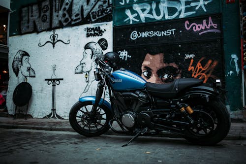 無料 落書きで壁の近くに駐車したオートバイの写真 写真素材