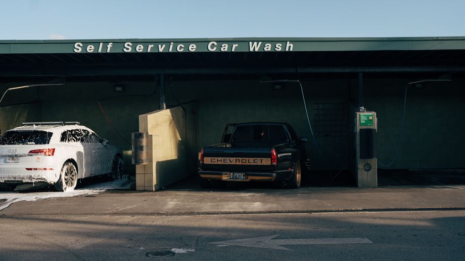 Self service car wash featuring a foam-covered Audi and a Chevrolet truck.