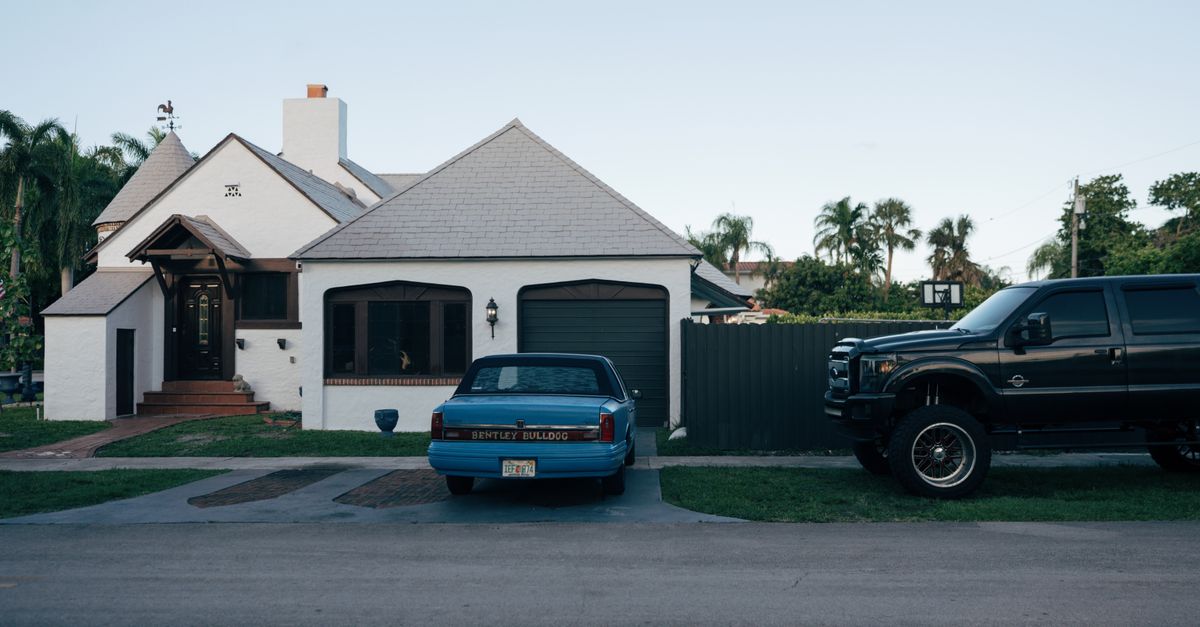 A suburban house with parked classic Bentley Bulldog and a modern truck.