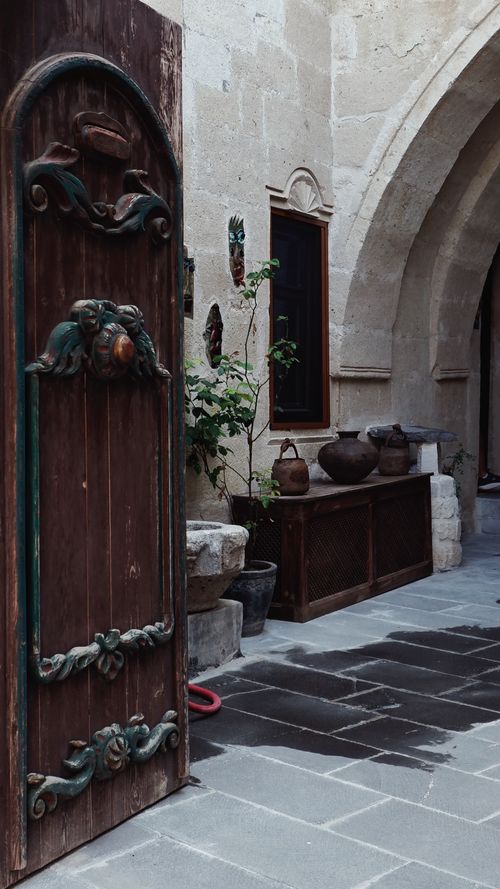 Free Charming rustic courtyard featuring an open vintage wooden door with intricate carvings. Stock Photo