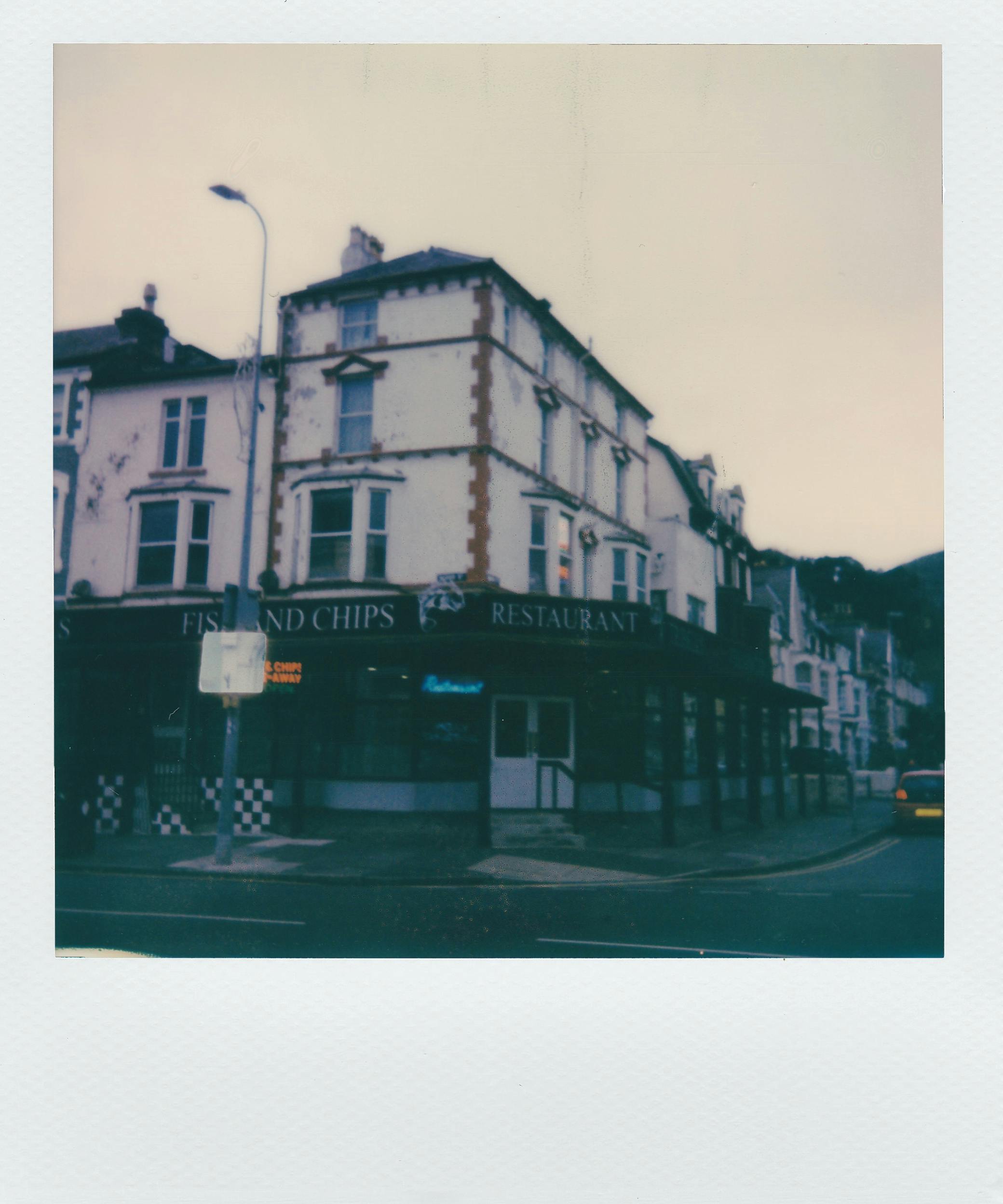 Free Retro style polaroid of a classic fish and chips restaurant on a street corner, showcasing nostalgic architecture. Stock Photo