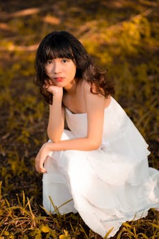 一位穿着白色连衣裙的优雅女子在树叶间优雅地摆着姿势