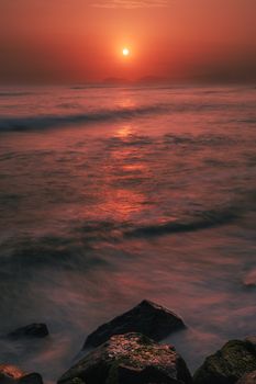 Tranquil sunset view over the Lima coastline with vibrant sky reflection on the ocean.