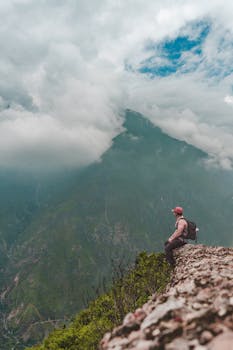A hiker on a rocky cliff admires the mountain scenery in Matucana, Peru.
