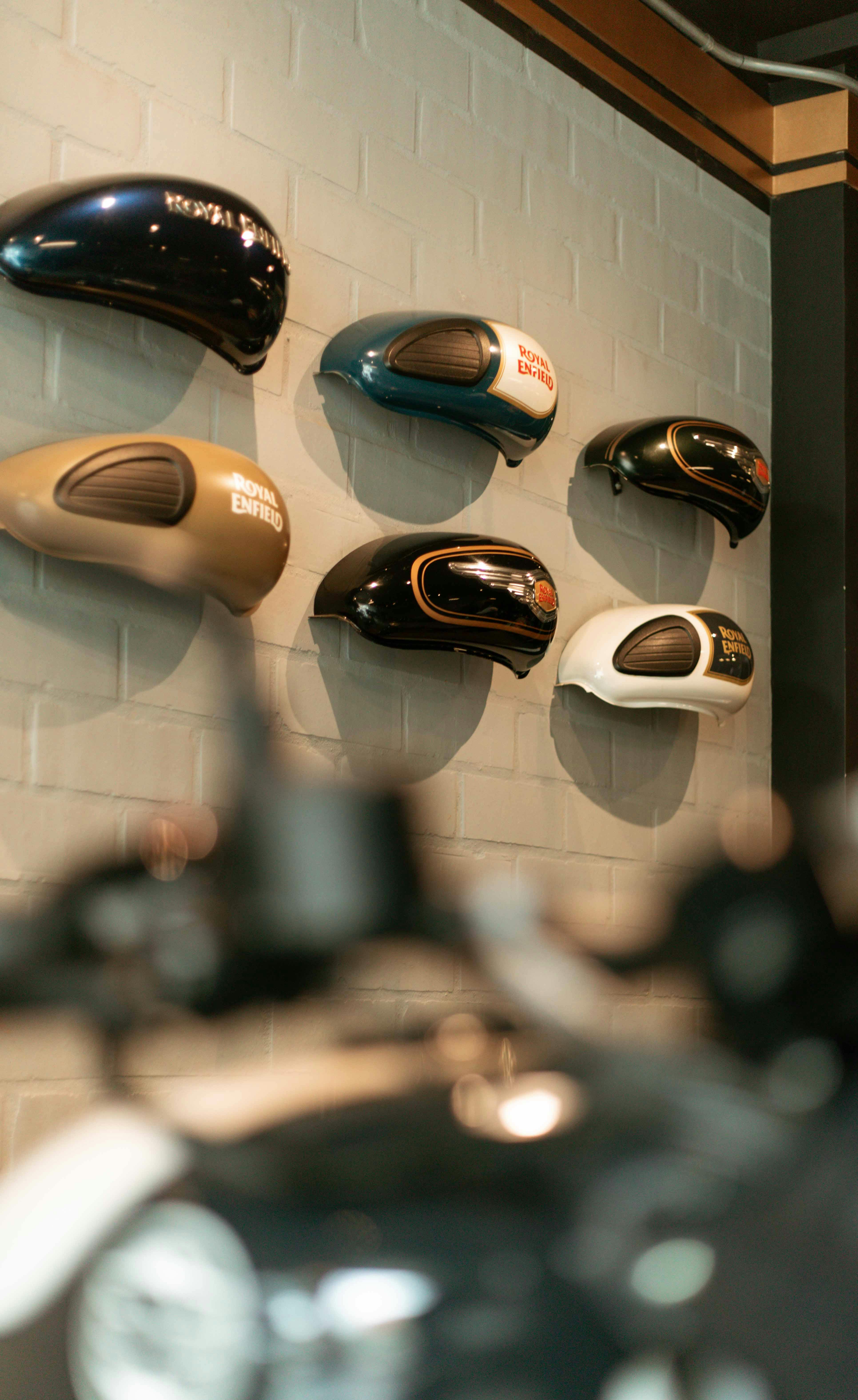 Colorful motorcycle gasoline tanks elegantly displayed on a wall indoors.