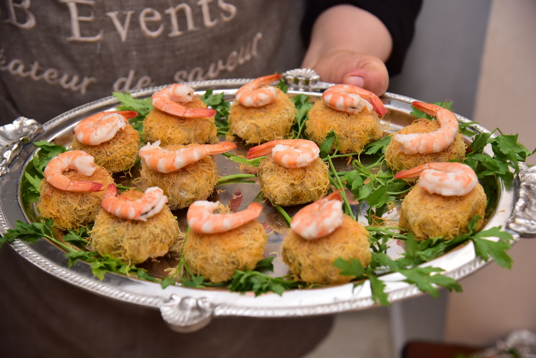 Delicious shrimp appetizers served elegantly on a silver platter with fresh greens.