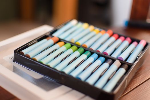 Close-up of colorful pastel chalks in a black case, perfect for art projects.