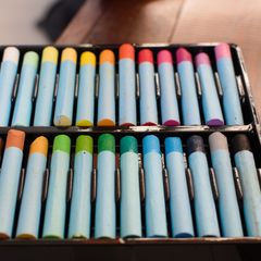 Two rows of wrapped oil pastels in a black box