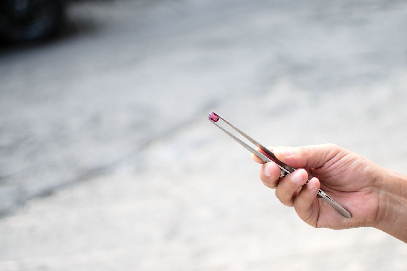 A dealer holding a gemstone in tweezers