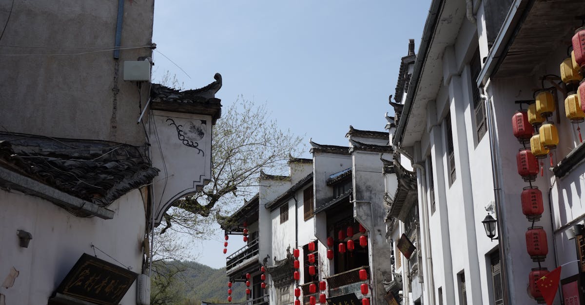 Quaint street in traditional Chinese architecture with red lanterns under a clear blue sky.
