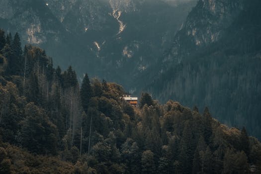 A lone cabin nestled in lush green mountains, offering serene seclusion and tranquility.