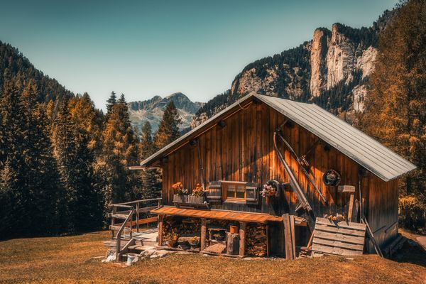 Timber cabin below a rock face in autumn, photo by Cătălin Todosia on Pexels