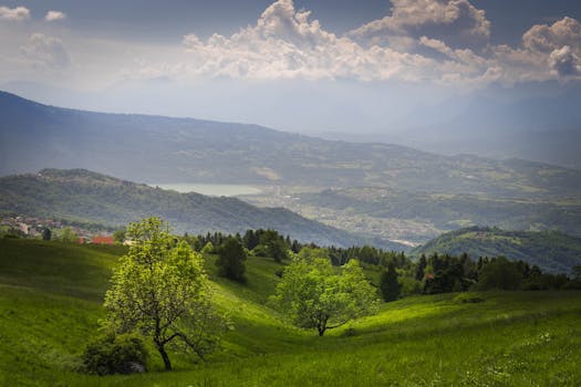 Breathtaking view of lush green hills and distant mountains under a cloudy sky.