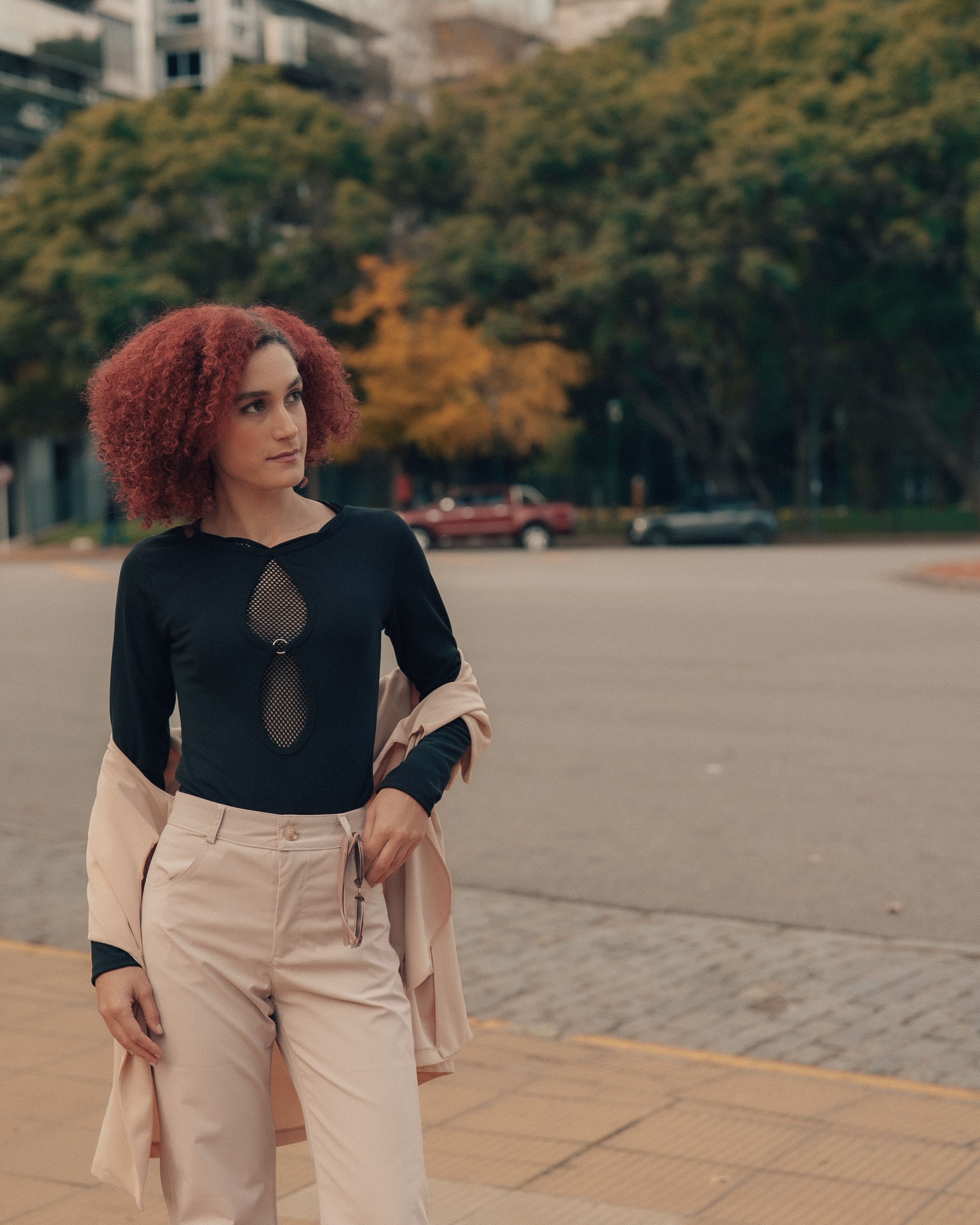 Mulher fashionista com cabelo vermelho posa com confiança no cenário urbano de Buenos Aires.