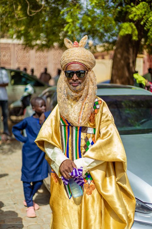 Free A man in vibrant traditional attire, wearing sunglasses, stands outdoors at a cultural event. Stock Photo
