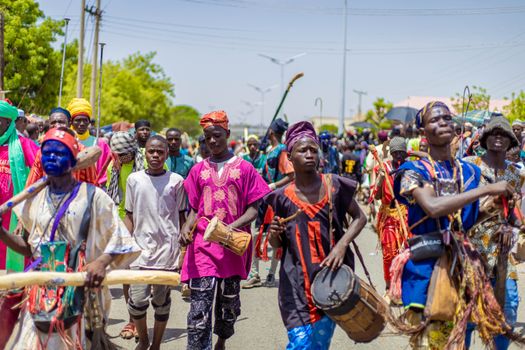 Colorful cultural festival with musicians and dancers in traditional attire on a bright day.