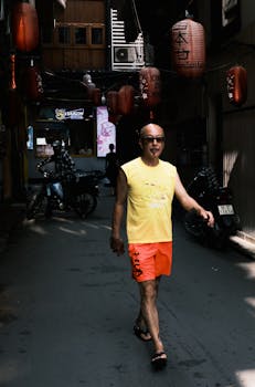A man walks down a Vietnamese street adorned with lanterns, capturing a candid urban moment.