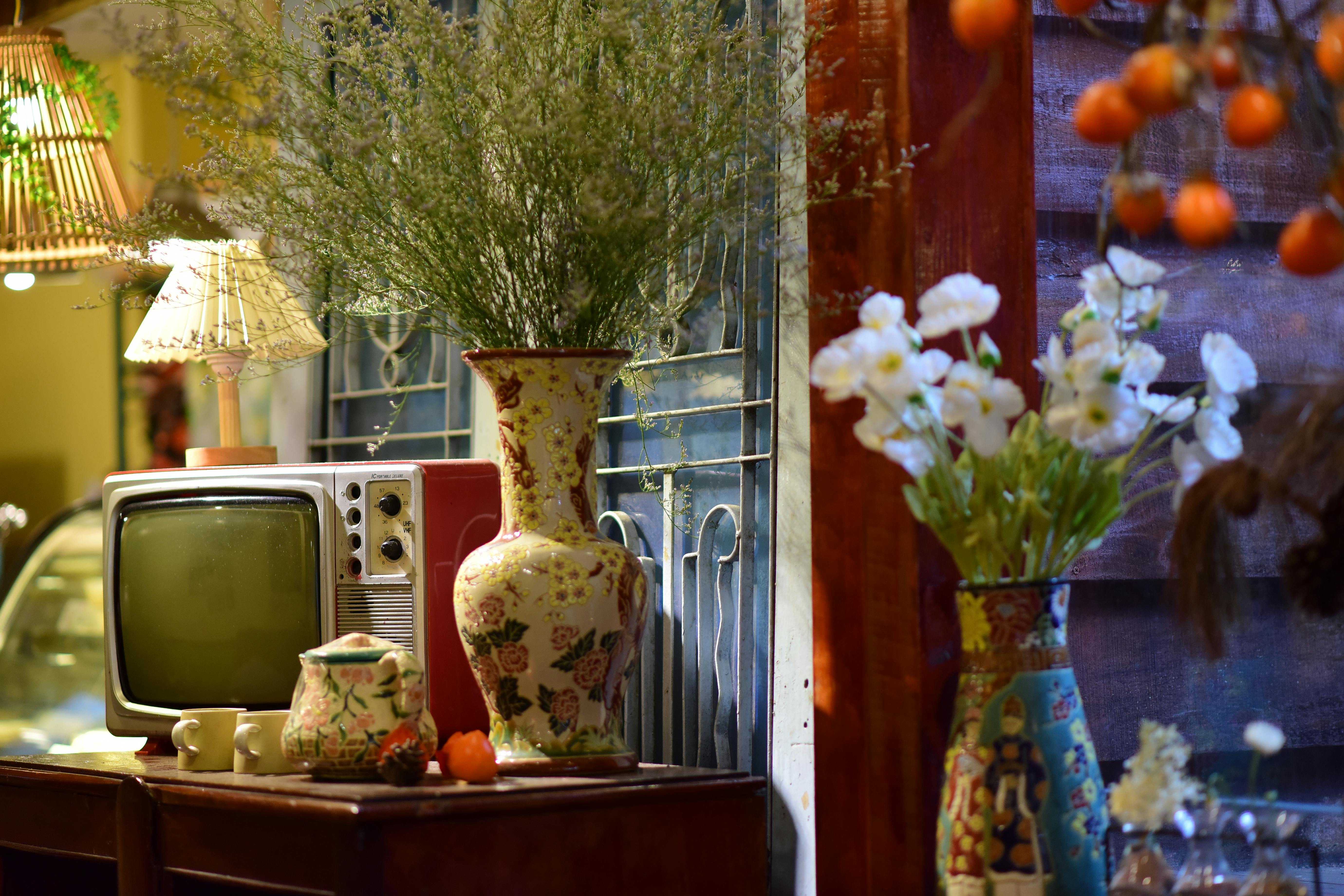 A charming vintage setup featuring a retro TV, floral vases, and a cozy ambiance.