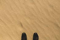 一双鞋置于沙质纹理的表面，营造出宁静简约的构图