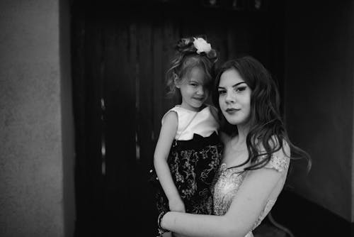 Grayscale Photo of Woman Carrying Girl