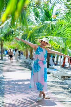 A smiling woman enjoying a sunny day at a tropical beach with palm trees.