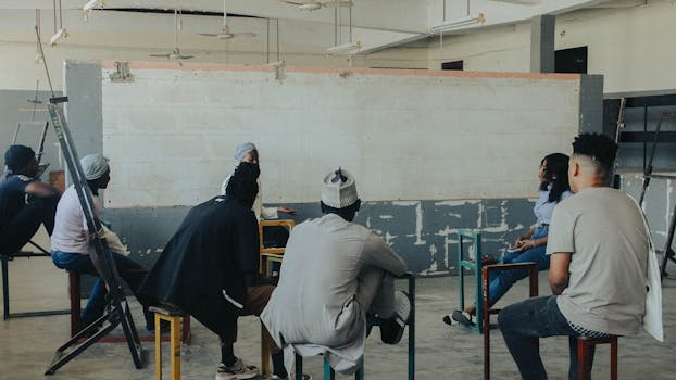 A diverse group of people engaged in a discussion in a minimalist classroom.
