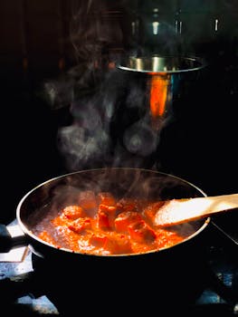 A flavorful curry cooking on a stove, captured with steam rising dramatically.